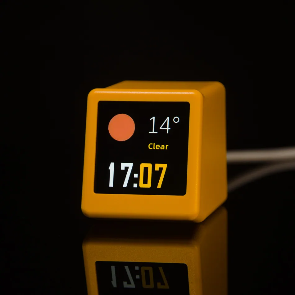 Yellow GeekMagic SmallTV Ultra showing the time and clear weather